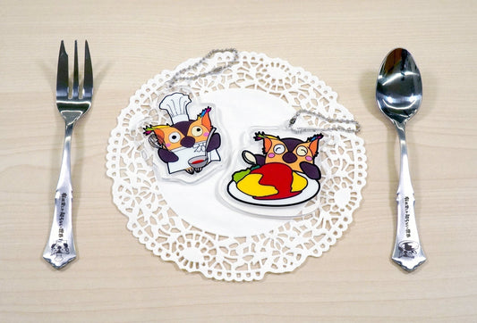 フォークとスプーンの間にオムライスとコックさんに扮したブッコローのアクリルスタンド